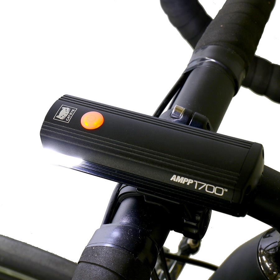 CatEye AMPP 1700 bike light with bright LED beam, mounted on a bicycle handlebar for enhanced visibility during night rides.