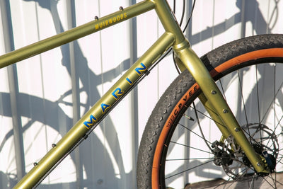Green and gold Marin Muirwoods urban city bicycle with sleek frame and ergonomic design, suitable for city commuting.