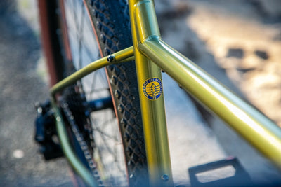 Green and gold Marin Muirwoods urban city bicycle with a sleek frame and fat tires, designed for city riding and commuting.