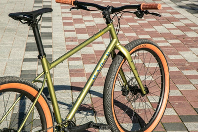 Green and gold Marin Muirwoods urban city bicycle with a sleek frame, suitable for city commuting and urban riding.
